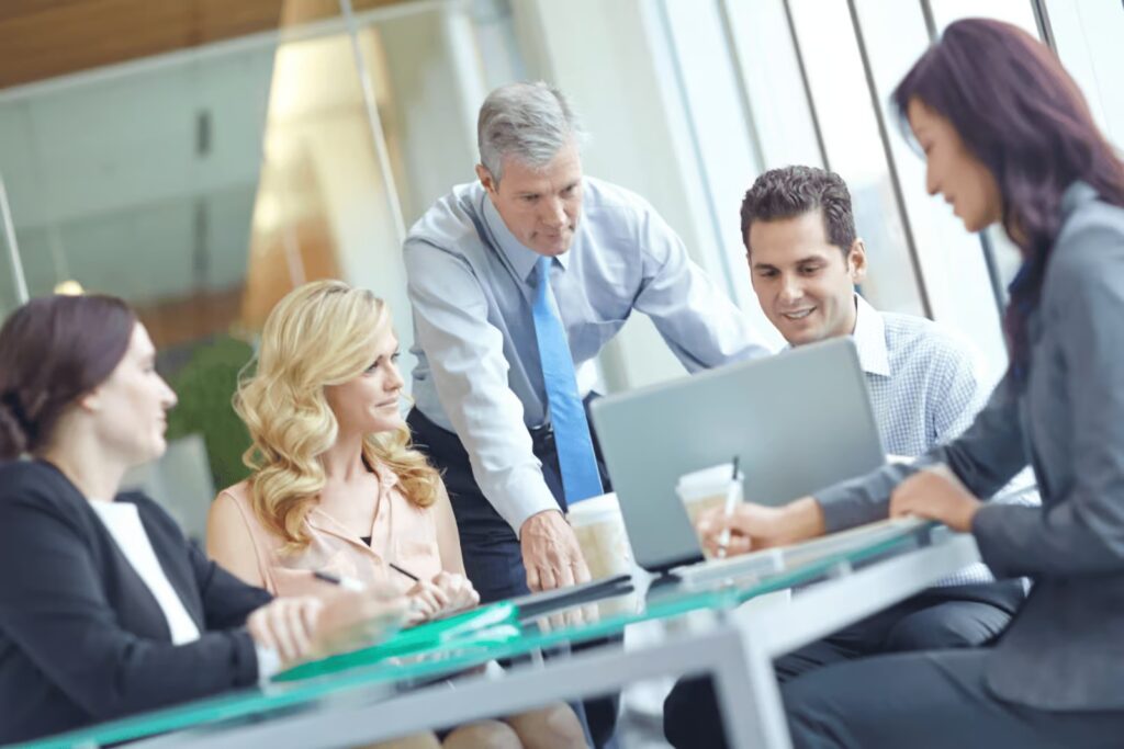 imgi_353_Business-team-gathered-around-a-laptop-in-a-modern-office-meeting